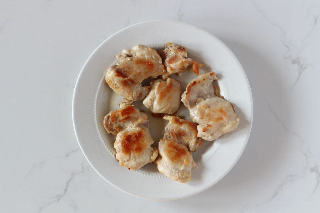 Cooked chicken thighs on white plate