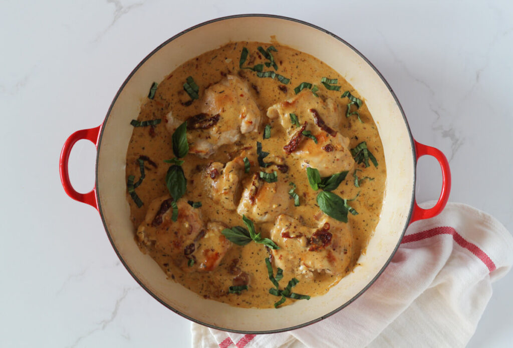 Finished healthy marry me chicken dish in saucepan topped with fresh basil
