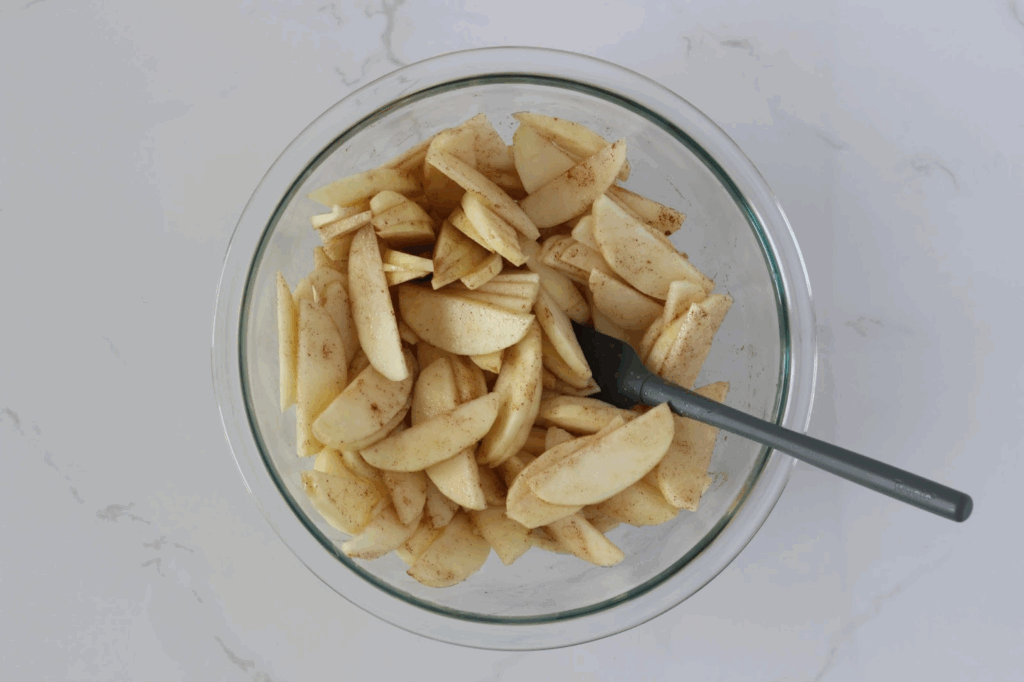 coating apple slices in bowl with small spatula