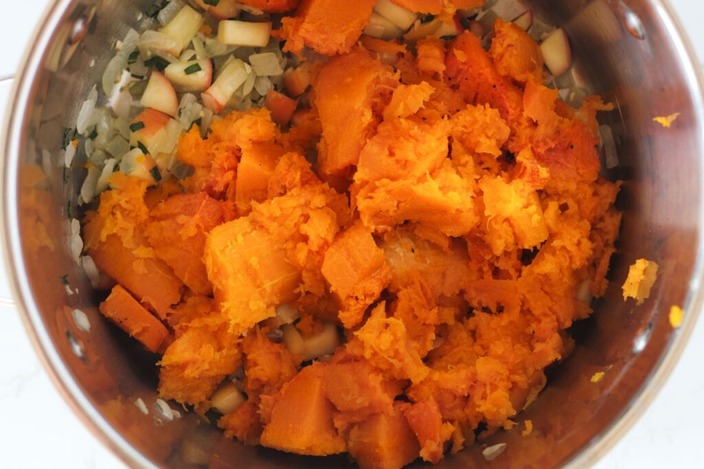 cooked butternut squash in stockpot with apple, onion, sage, and garlic