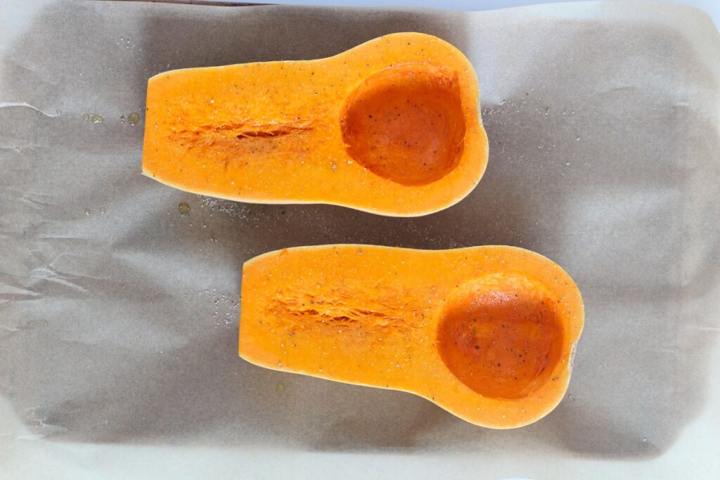 butternut squash halves on baking sheet lined with parchment paper