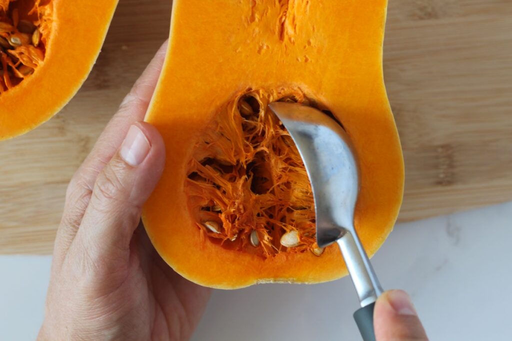 scooping butternut squash seeds and pulp with ice cream scooper
