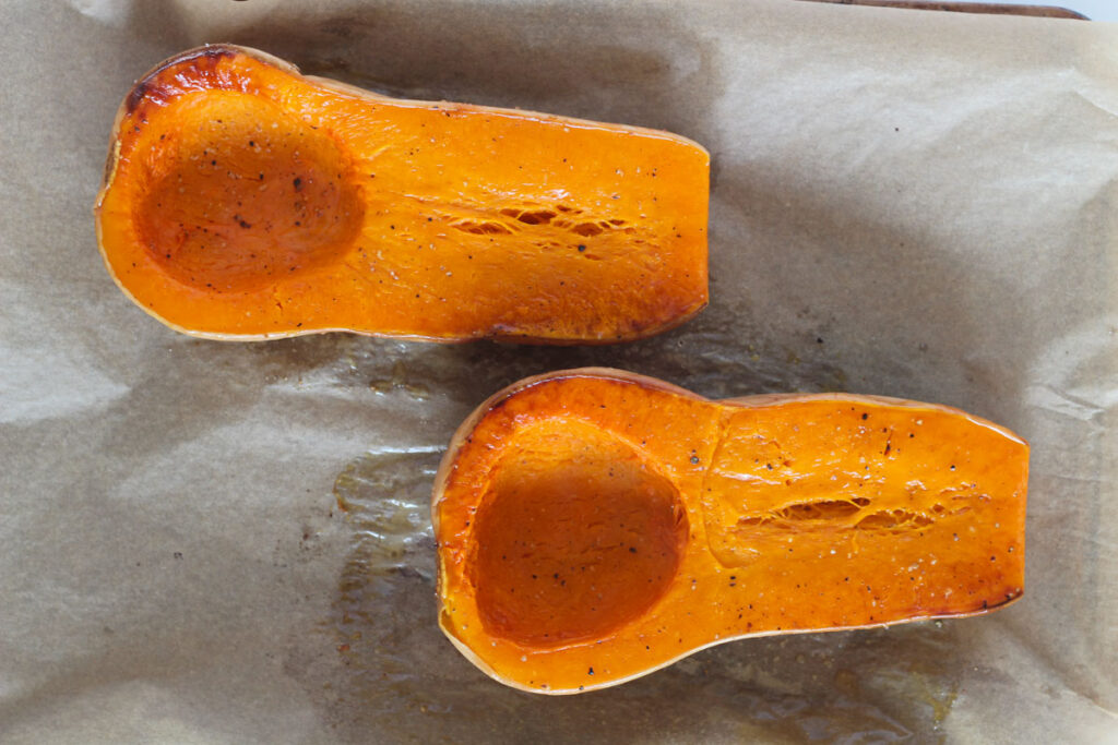 roasted butternut squash halves on baking sheet lined with parchment paper