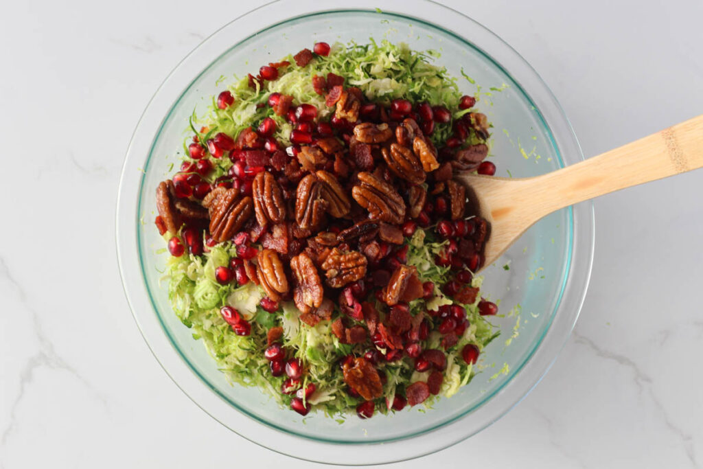 Mixing Brussels sprouts salad ingredients in glass bowl with wooden spoon