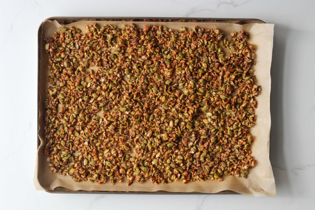 Unbaked granola spread on baking sheet lined with parchment paper