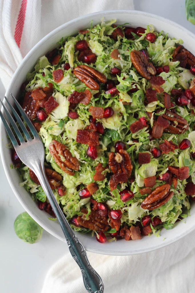 Brussels sprouts salad in white bowl with fork on the side