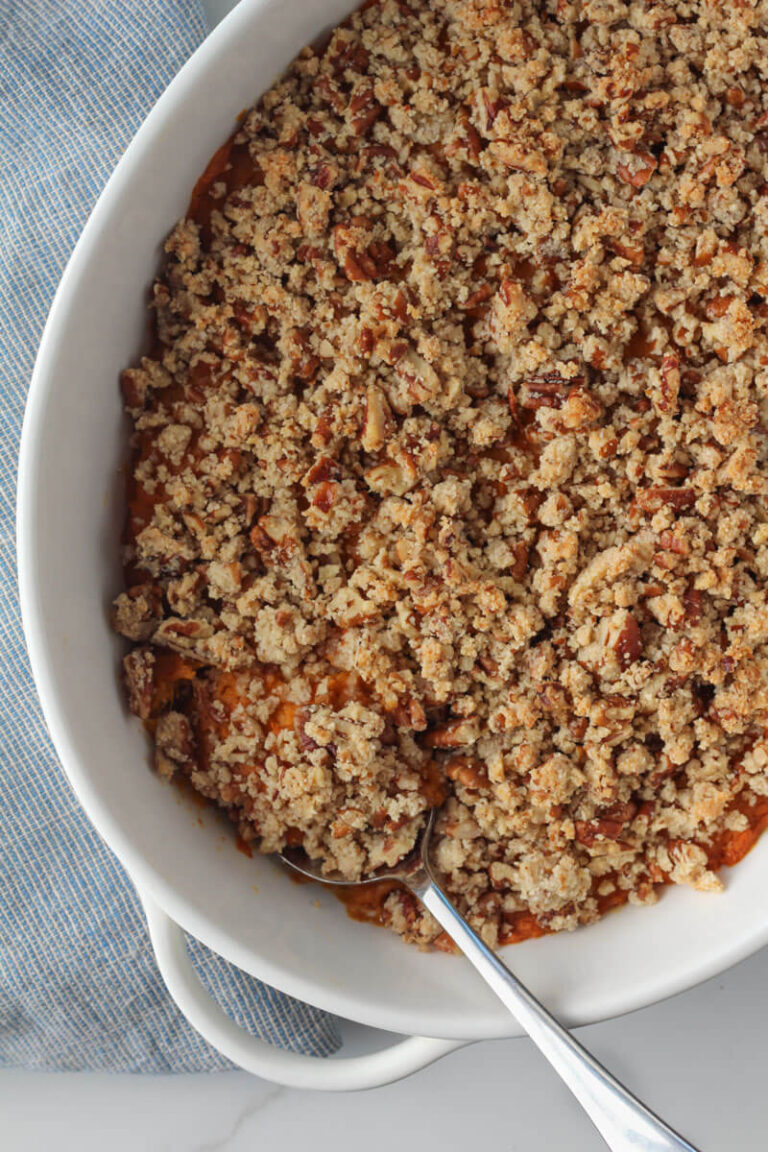 healthy sweet potato casserole in oval white casserole dish with silver serving spoon
