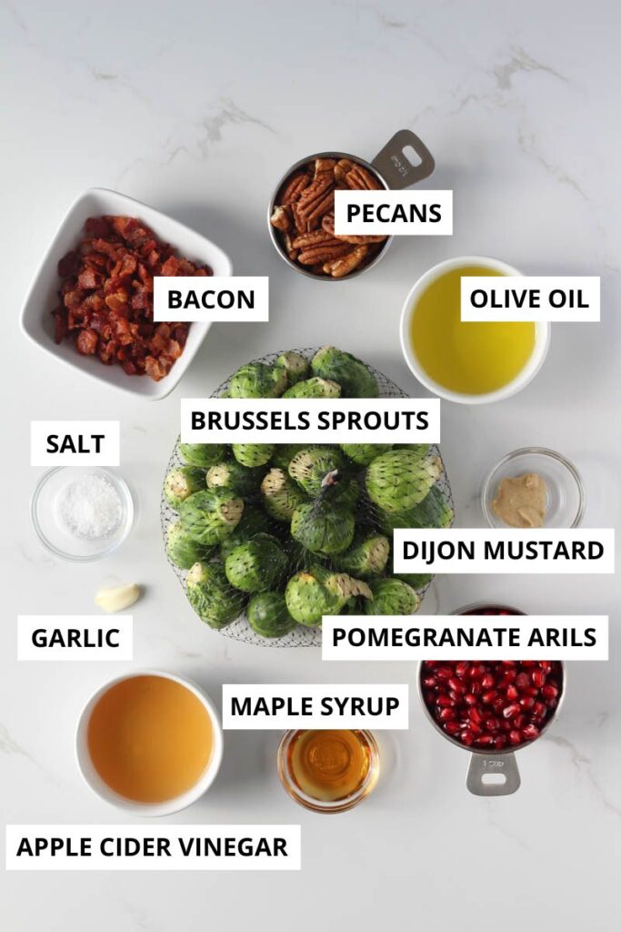 Brussels sprouts salad ingredients in small bowls on marble counter labeled