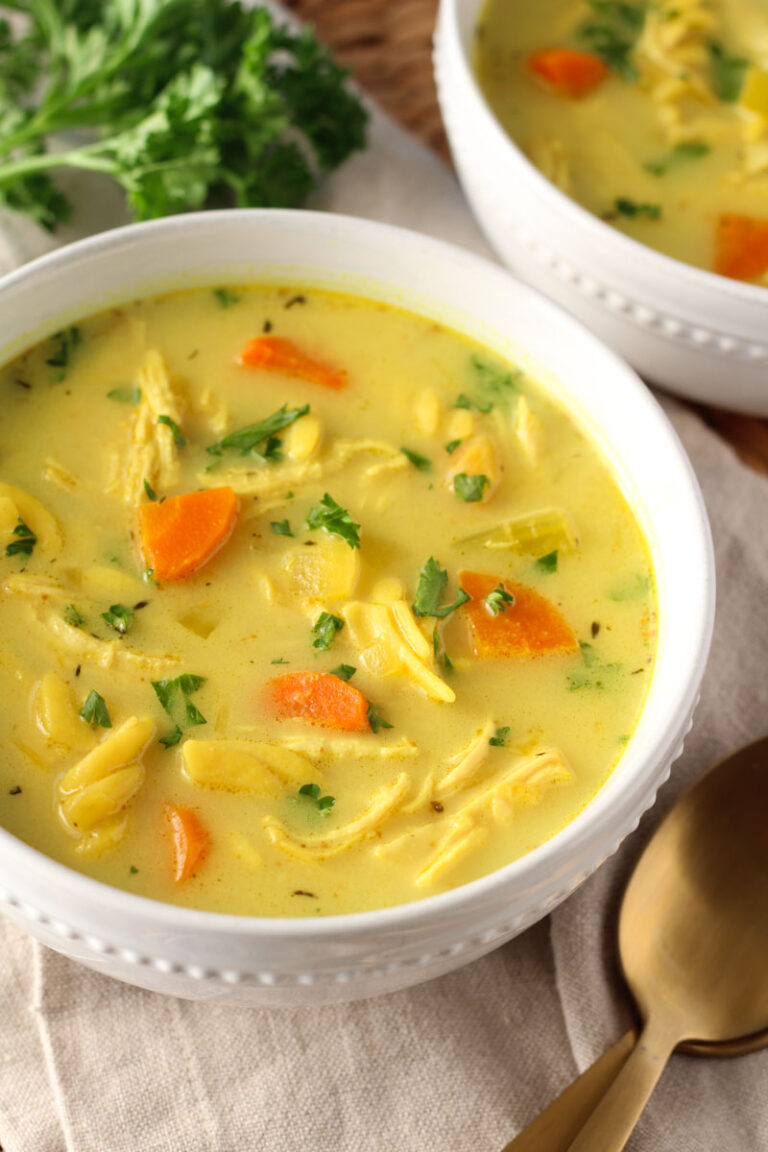 turmeric chicken noodle soup in small white bowl with spoon